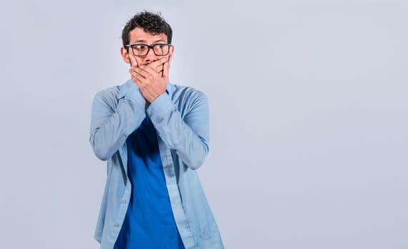 Surprised man covering his mouth looking to the side, Surprised man in glasses covering his mouth looking to the side, concept of man keeping a secret