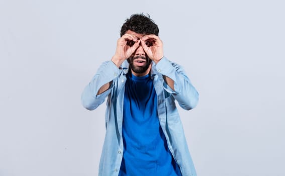 Man making binoculars gesture, Curious man making binoculars gesture, Guy on isolated background making binoculars gesture, man using his fists as binoculars