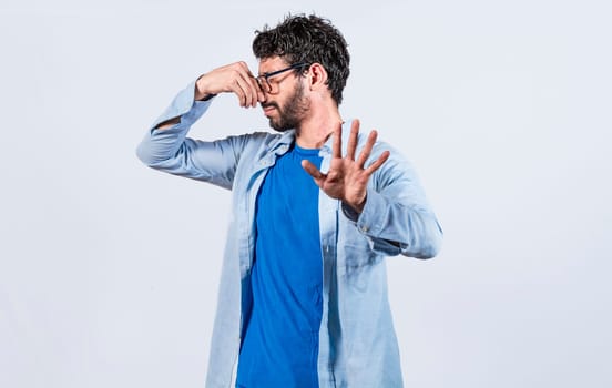 Confused unhappy man grabbing nose with fingers and stretching hand out feeling disgusted, A man with covering his nose