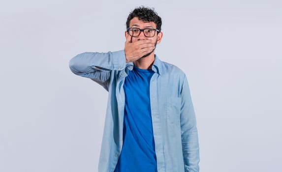 Surprised man covering his mouth on isolated background, Surprised man in glasses covering his mouth, concept of astonished man covering his mouth