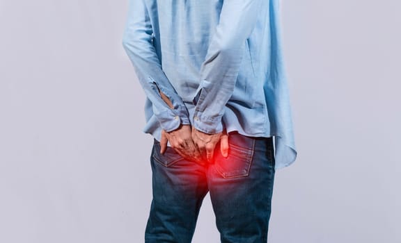 Man with digestive problem touching his buttock, man with hemorrhoid problem on isolated background, Man with diarrhea problem