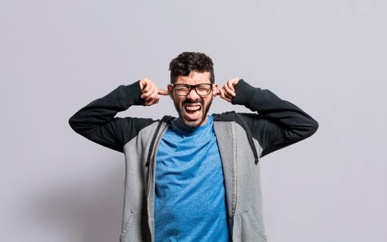 Irritated person screaming covering his ears, desperate person avoiding hearing bad news, stressed man screaming covering his ears