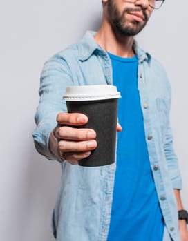 Close up of person offering a coffee to go, Young man offering the camera a coffee to go, Handsome man holding a coffee to go isolated