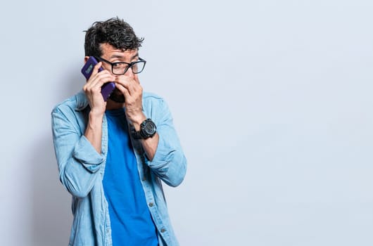Person secretly talking on the phone. Young man secretly talking on the phone isolated, A guy secretly talking on the phone