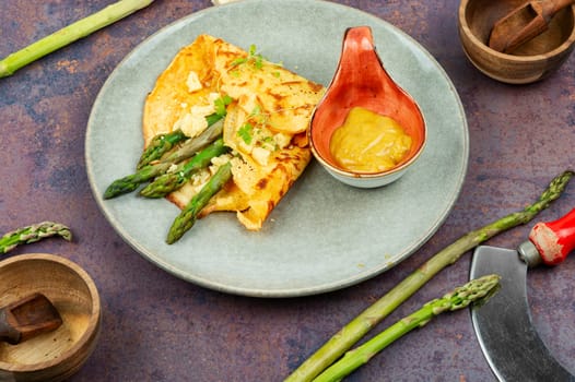 Tasty omelet or vegan crepes stuffed with green asparagus,cheese and herbs. Healthy breakfast.