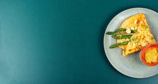 Tasty omelet or vegan crepes stuffed with green asparagus,cheese and herbs. Healthy breakfast.