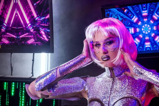 close-up of blonde as cyber robot. Girl in shining silver armor in neon, in glowing glasses. screens glow behind her. Blonde with fantastic makeup, posing in cyberspace.