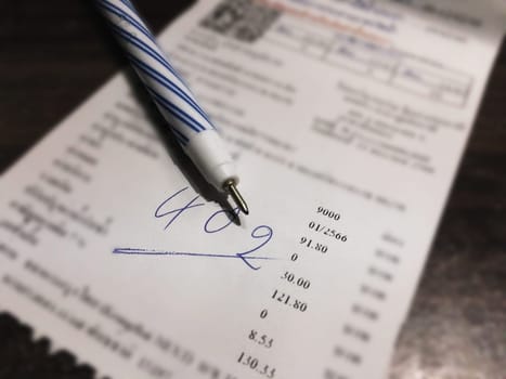 Bill and pen on dark wooden table, Bill for income and expenditure in still life tone