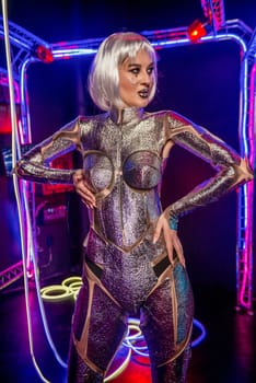 blonde as cyber robot. Girl in shining silver armor in neon. Blonde with fantastic makeup and image in dark key and color light, posing in cyberspace. screens and wires glow around.