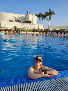 Young girl in sunglasses in the water of a swimming pool