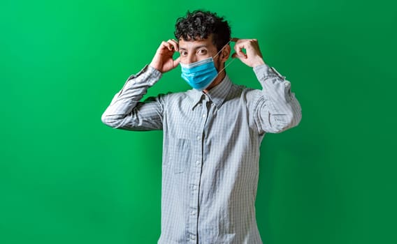 A man putting on the mask on isolated background, Handsome man putting on a surgical mask isolated. Concept of a person correctly putting on a surgical mask isolated