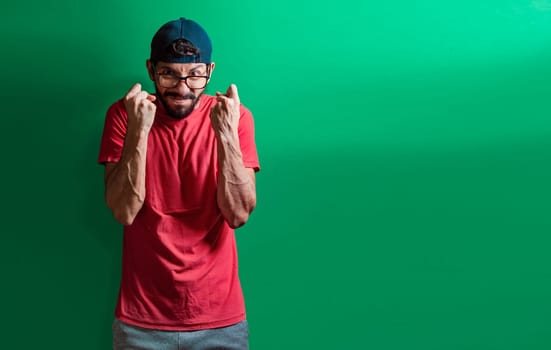 Man with angry expression isolated, man in cap with anger expression on isolated background, concept of angry person clenching fists, aggressive people showing fists