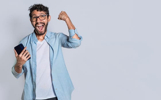 Excited man winning a prize from his cellphone. Excited handsome man looking at smartphone celebrating something. Happy person holding a smartphone and celebrating