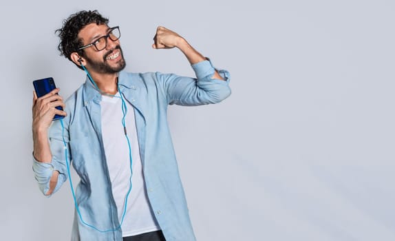 Happy handsome man with headphones holding a cell phone and celebrating, Happy person using his smartphone and celebrating victory isolated