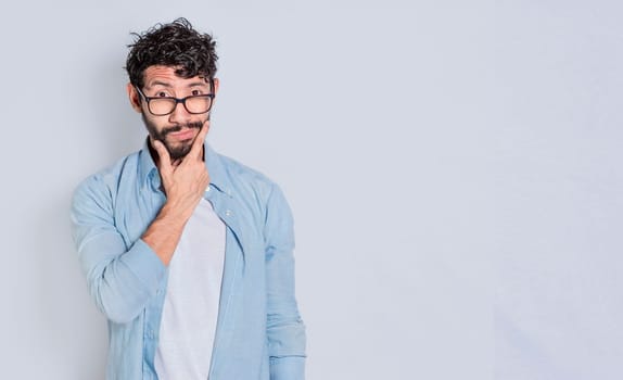 Handsome man rubbing his beard with a doubtful expression, Person rubbing his chin with a doubtful expression. handsome bearded man with doubt expression isolated