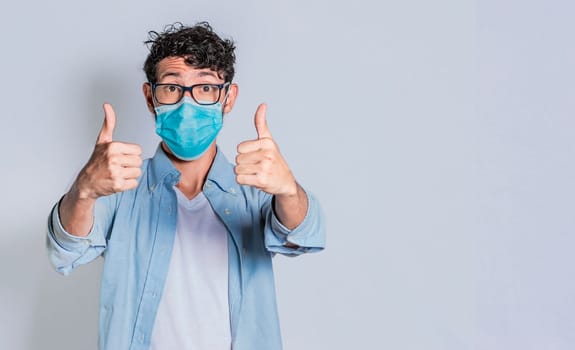 Man wearing medical mask and giving thumbs up, Isolated person wearing medical mask giving thumbs up.