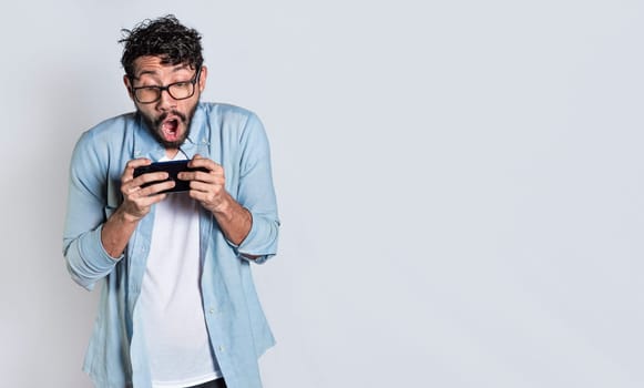 Surprised people watching an advertisement on their cell phone. Amazed man holding cell phone horizontally on isolated background, Person gasping and playing games on his mobile