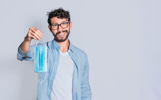 Smiling man offering you a surgical mask on isolated background, Person offering you a medical mask isolated