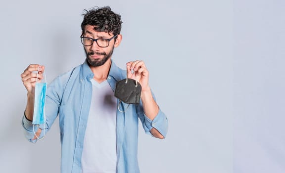 Handsome man deciding which surgical mask to wear, Person deciding to wear a surgical mask isolated, Concept of people deciding which mask to wear