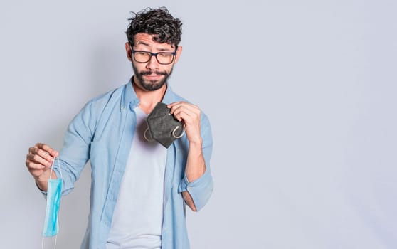 People deciding which surgical mask to wear, Person deciding to wear a medical mask in an isolated context, Isolated man deciding which medical mask to wear