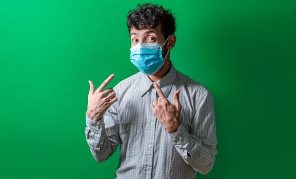Isolated man wearing double surgical mask pointing to them with thumbs, Person wearing double mask with thumbs up. Concept of the double use of surgical mask.