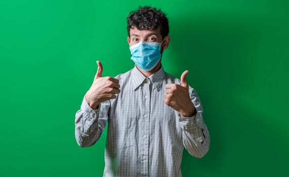 Isolated man with mask on giving thumbs up, Person giving thumbs up with mask on isolated. Concept of the correct use of the surgical mask.