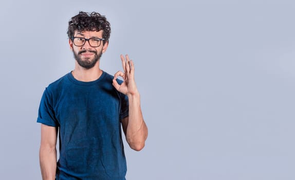 Handsome man gesturing everything is ok, Person making ok gesture, Smiling man showing ok gesture looking at camera, expression of everything is fine.