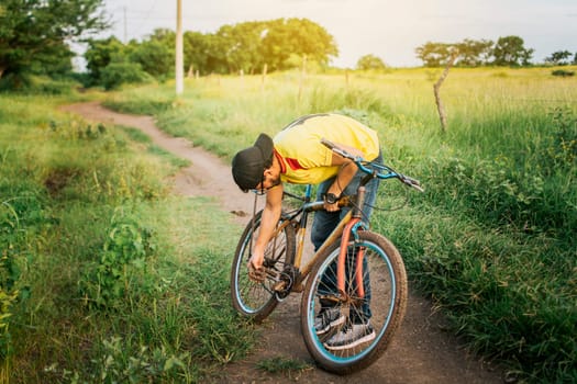 Man repairing his bike in the middle of the road, Man in the countryside repairing his bike, Traveler person repairing his bike on the road