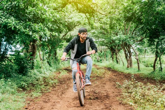 Teenage guy riding a bike in the countryside, Portrait of a guy in cap riding a bike on a country road, Person riding a bike in the countryside, Bicyclist person on his bike on a country road forest