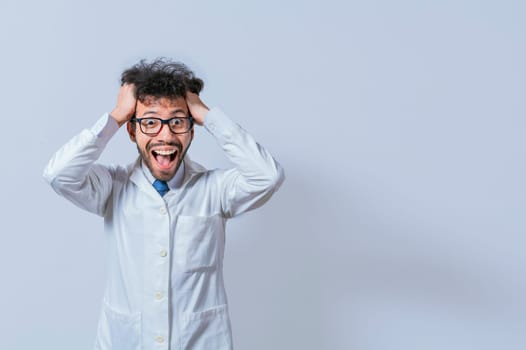 A mad scientist pulling his hair out on isolated background. Mad scientist grabbing his hair with a mad face isolated. A doctor with a crazy face looking at the camera