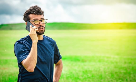 Man calling by cell phone, young man in the field calling by cell phone