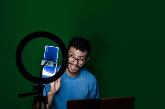 Student receiving online classes. Man receiving online classes with phone. Guy with laptop making video blog on phone. Online classes concept. Guy on a video call working from home