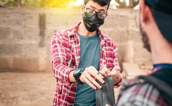 Two young people giving each other a mask, View of a young man giving a surgical mask to another person, concept of a person giving a surgical mask