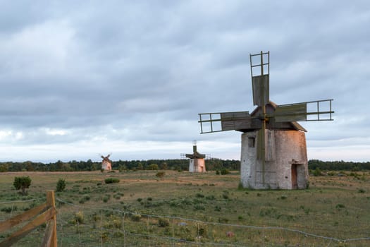 Windmills in Field in Gotland, Sweden with clouds behind them.