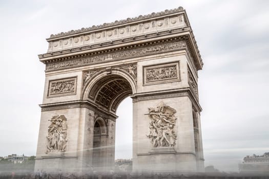 Arch of Triumph in Paris, France with cloudy sky.
