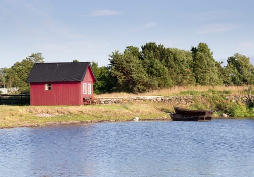 Red House by Rowing Boats and water with blue sky.