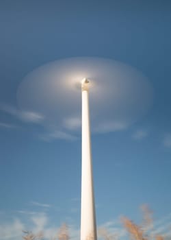 Wind Power Station Spinning Fast with blue sky and some clouds.