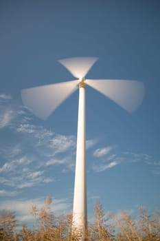 Wind Power Station Spinning Fast with blue sky and some clouds.