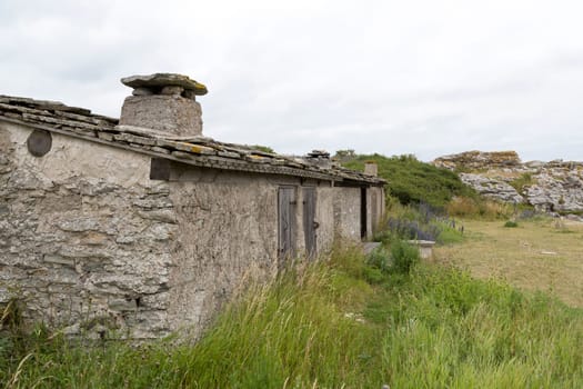 Old Fishing Hut in Gotland, Sweden with sea stacks next to it.