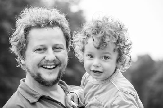 Portrait of 1 year old baby boy in father s arms.