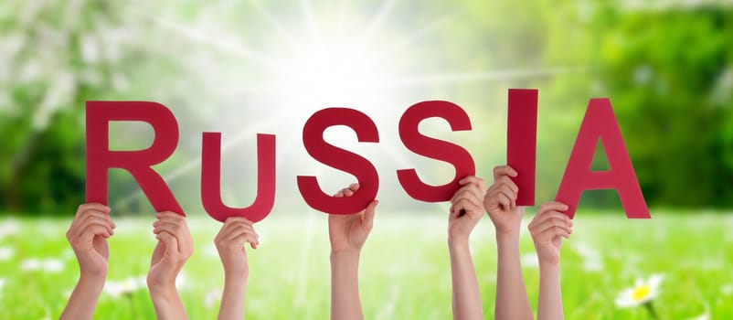 People Or Persons Hands Building English Word Russia. Sunny Green Grass Meadow As Background.