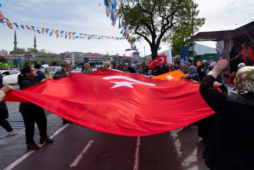 Istanbul, Turkey - May 3 2023: AK Party supporters waving a big Turkish flag in front of AK Party tent in the neighbourhood of Uskudar during 2023 elections