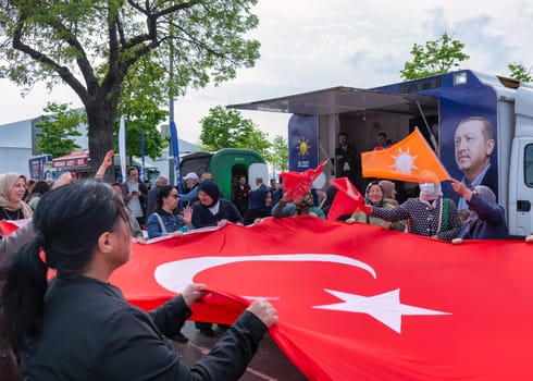 Istanbul, Turkey - May 3 2023: AK Party supporters waving a big Turkish flag in front of AK Party tent in the neighbourhood of Uskudar during 2023 elections