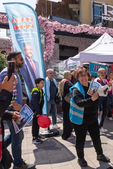Istanbul, Turkey - May 13 2023: Woman holding election campaign brochure in front of Republican Peoples Party kiosk in the neighbourhood of Ortakoy during the 2023 elections