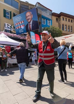 Istanbul, Turkey - May 13 2023: Man waving a big poster with Kemal Kilicdaroglu photo in front of Republican Peoples Party kiosk in the neighbourhood of Ortakoy during the 2023 elections