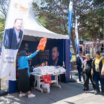 Istanbul, Turkey - May 13 2023: AK Party supporter waving party flag in front of AK Party tent in the neighbourhood of Ortakoy during 2023 elections