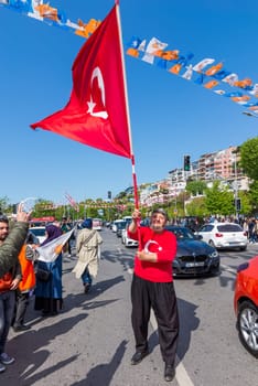 Istanbul, Turkey - May 13 2023: Supporter of AK Party waving a big Turkish flag in the street at the neighbourhood of Uskudar during 2023 elections
