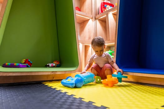 Little child enjoying playtime with colorful toys in a modern and interactive indoor playroom