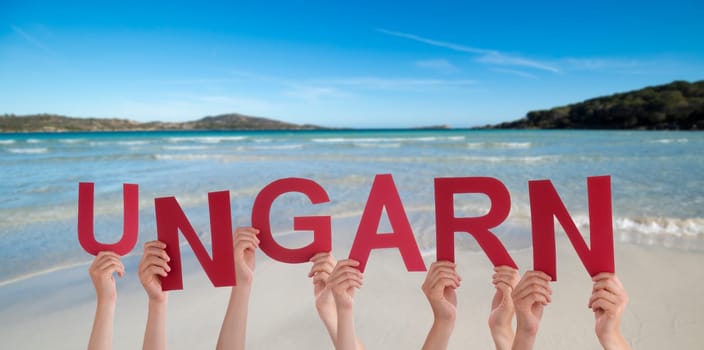 People Or Persons Hands Building German Word Ungarn Means Hungary. Summer Ocean, Sea And Beach As Background.