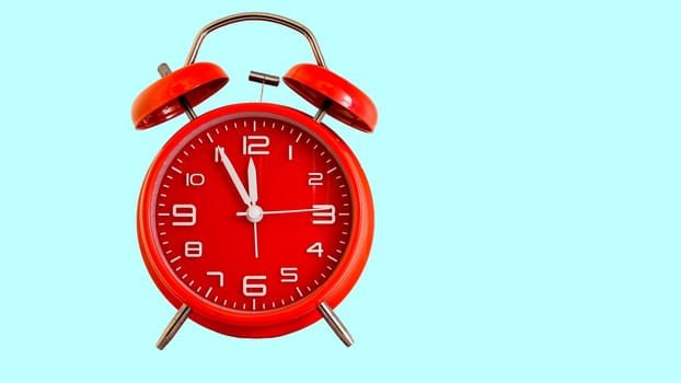 Red alarm clock isolated on light blue colored background